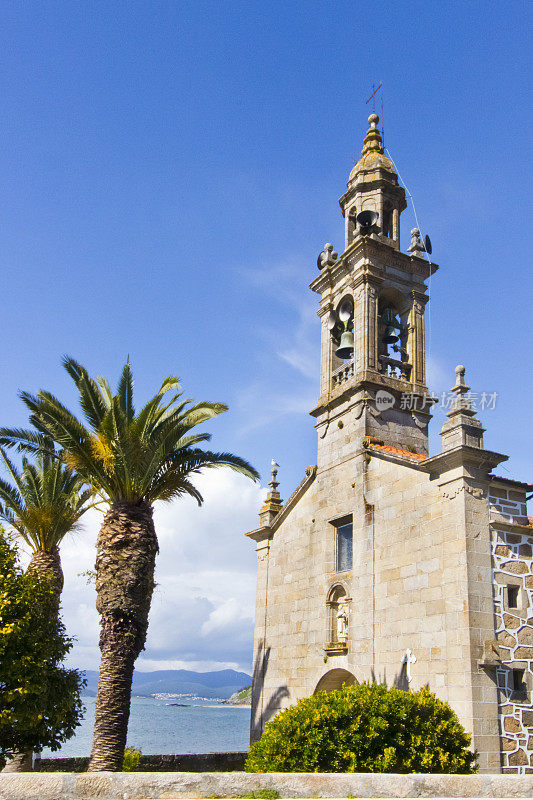 圣文森特de Noal钟楼和教堂正面在波尔图多孙，Coruña省，加利西亚，西班牙。棕榈树，海景和晴朗的天空。